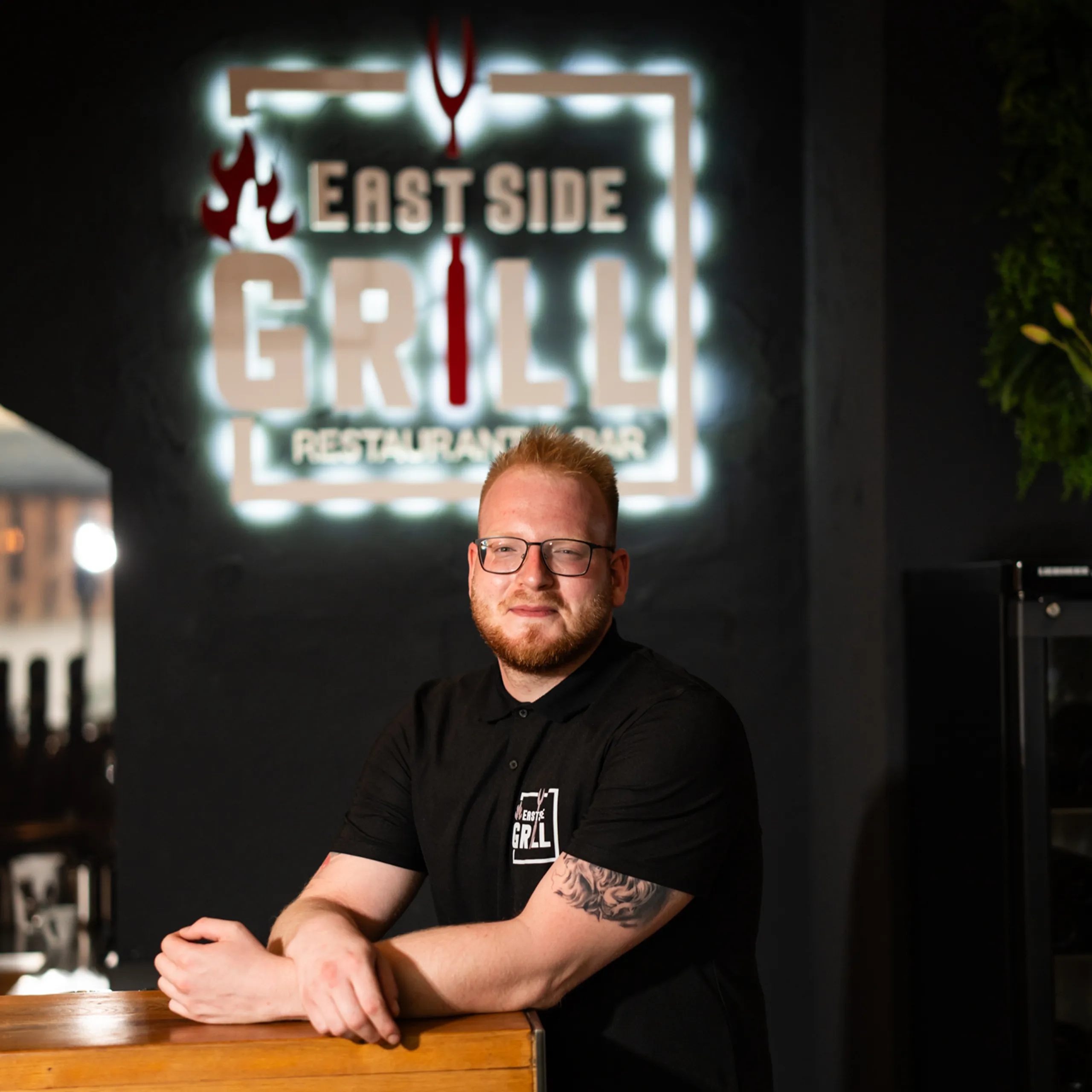 Branko Vujanovic, Chefkoch und Geschäftsführer des EastSide Grill, im Restaurant vor dem beleuchteten Logo